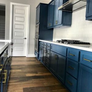 Cabinet painting in Sacramento, CA by Baldwin Custom Painting — navy blue kitchen cabinets with brass pulls and white countertops