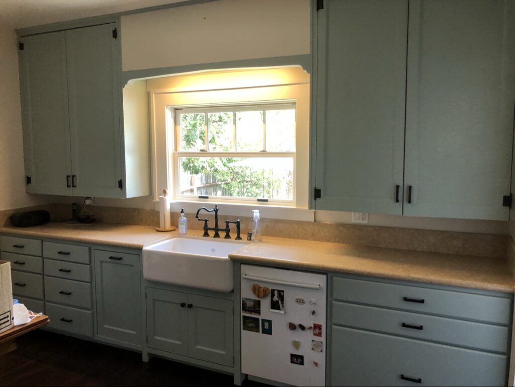 Cabinet painting in Sacramento, CA by Baldwin Custom Painting — sage green kitchen cabinets with farmhouse sink and black fixtures