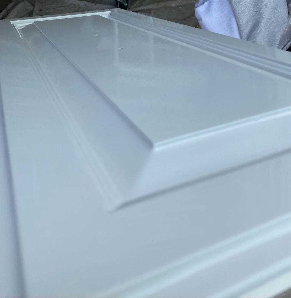 Cabinet painting in Sacramento, CA by Baldwin Custom Painting — close-up of a freshly sprayed white cabinet door showing a flawless glossy finish