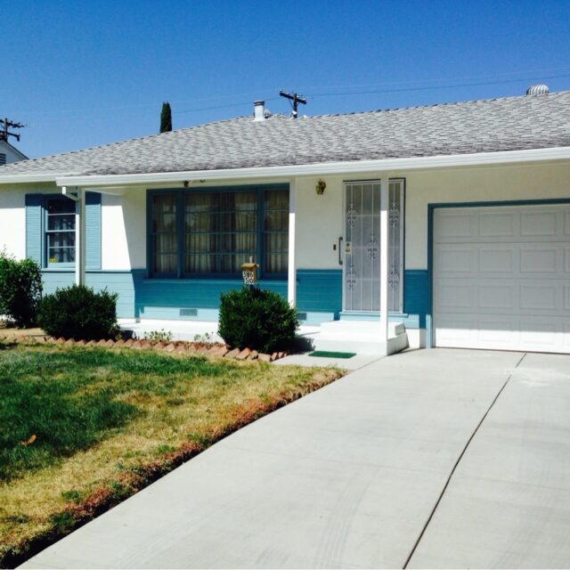 Exterior house painting in Sacramento, CA by Baldwin Custom Painting — white ranch home with teal shutters and garage