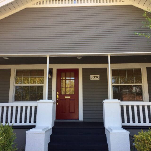 Exterior house painting in Sacramento, CA by Baldwin Custom Painting — bungalow with stone pillars and red front door