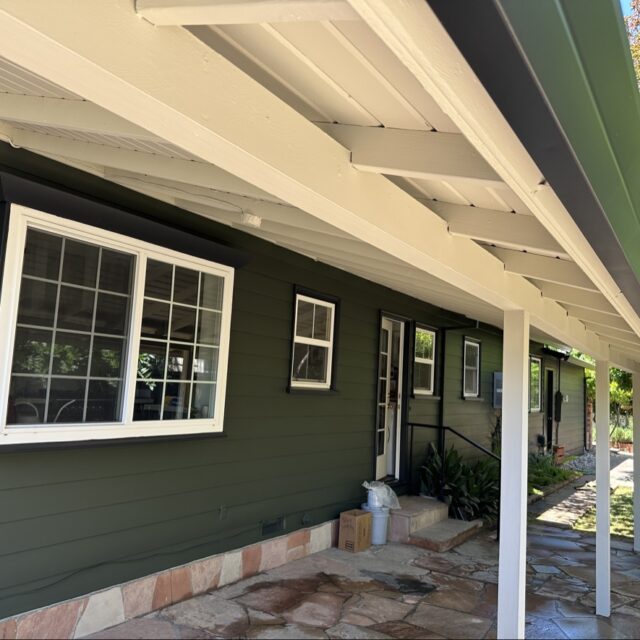Exterior house painting in Sacramento, CA by Baldwin Custom Painting — dark green home with covered porch and wood ceiling
