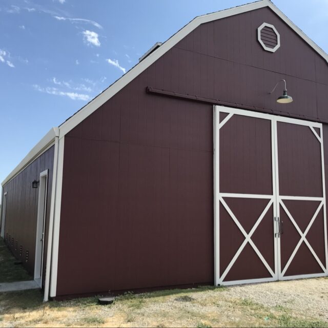 Exterior house painting in Sacramento, CA by Baldwin Custom Painting — red barn-style building with white trim