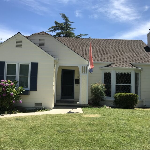 Exterior house painting in Sacramento, CA by Baldwin Custom Painting — white cottage with dark shutters and small porch