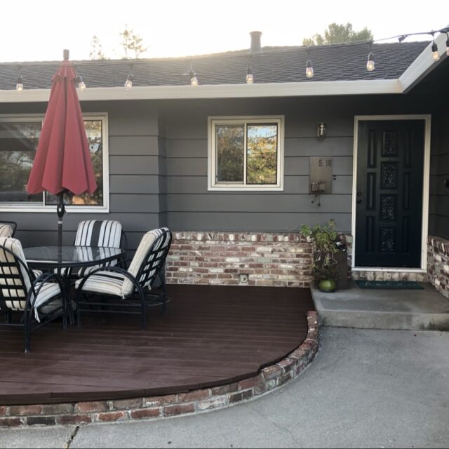 Exterior house painting in Sacramento, CA by Baldwin Custom Painting — gray single-story home with stone veneer and patio umbrella