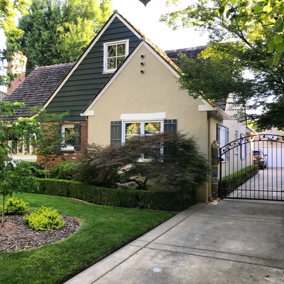 Exterior house painting in Sacramento, CA by Baldwin Custom Painting — tan craftsman bungalow with dark trim and green lawn