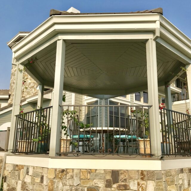 Exterior house painting in Sacramento, CA by Baldwin Custom Painting — looking up at a freshly painted white eave, porch ceiling, and posts under a brown roof edge