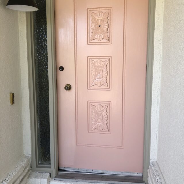 Exterior house painting in Sacramento, CA by Baldwin Custom Painting — close-up of a freshly painted salmon-pink front door with decorative panels and wall sconce