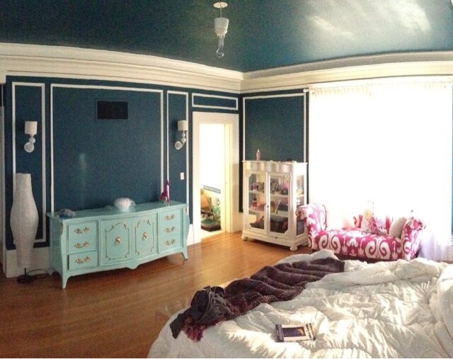Interior house painting in Sacramento, CA by Baldwin Custom Painting — bedroom with dark teal walls, white trim molding, hardwood floors and coordinated furnishings