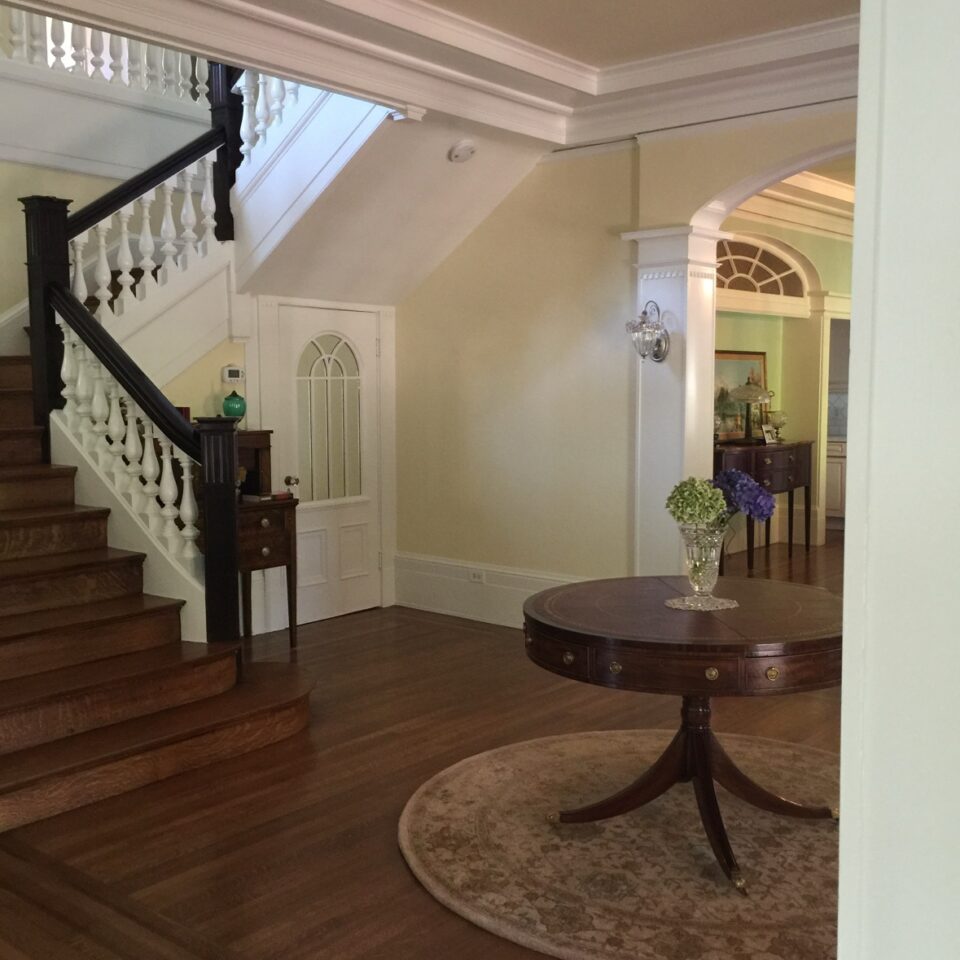 Interior house painting in Sacramento, CA by Baldwin Custom Painting — Painted staircase and entryway with white balusters and dark wood handrail