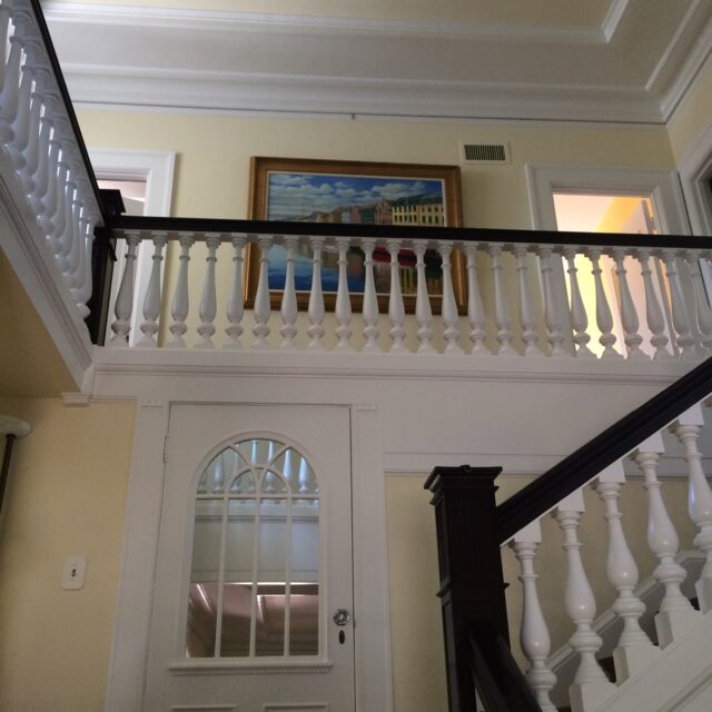 Interior house painting in Sacramento, CA by Baldwin Custom Painting — stairwell with white painted balusters, dark wood handrail, cream walls and coffered ceiling detail