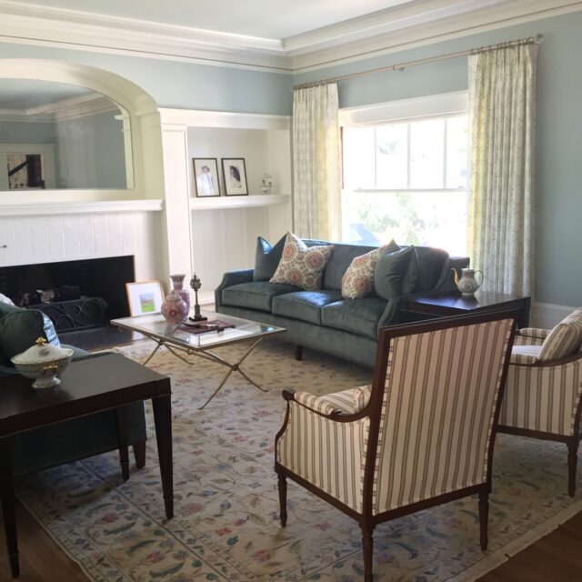 Interior house painting in Sacramento, CA by Baldwin Custom Painting — living room with light blue walls, white crown molding and trim, arched mirror and built-in shelving