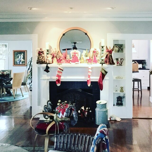 Interior house painting in Sacramento, CA by Baldwin Custom Painting — living room fireplace mantel with holiday decorations, round mirror and white built-in shelving