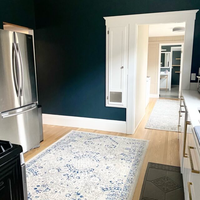 Interior house painting in Sacramento, CA by Baldwin Custom Painting — kitchen with dark green walls, white trim around doorways and stainless appliances
