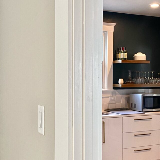 Interior house painting in Sacramento, CA by Baldwin Custom Painting — close-up of crisp white trim molding against a dark painted wall with wooden shelf