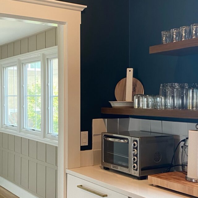 Interior house painting in Sacramento, CA by Baldwin Custom Painting — dark teal wall with white crown molding and door trim, wooden floating shelves