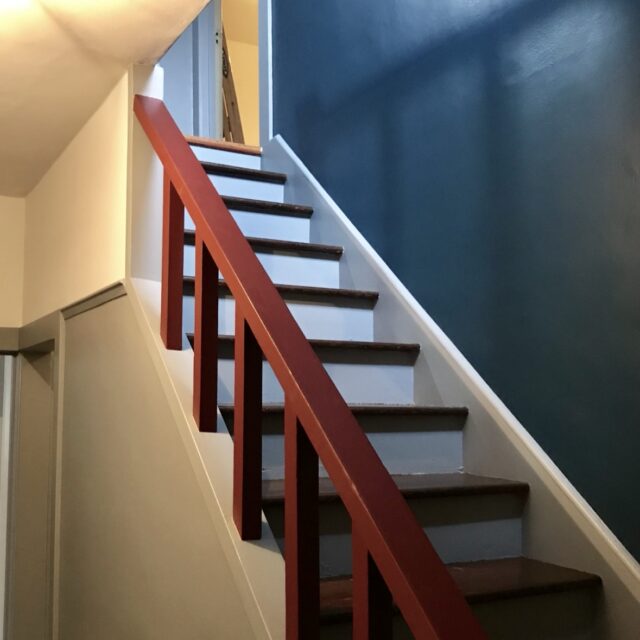 Interior house painting in Sacramento, CA by Baldwin Custom Painting — stairwell with blue accent wall, white trim and red handrail